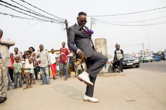 Ein Sapeur im grauen Anzug tanzt in den Straßen von Brazzaville