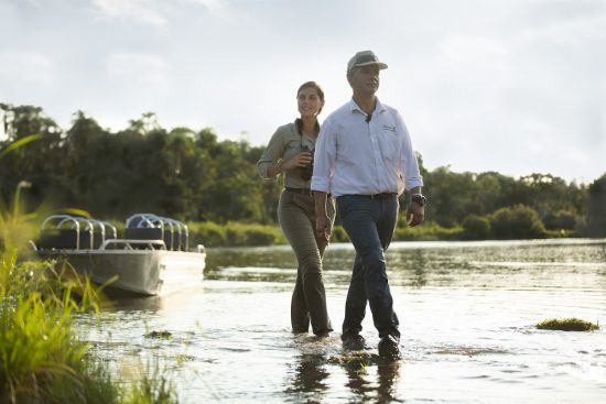 Mann und Frau schreiten nach einer Bootstour durchs Wasser