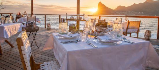 Gedeckter Tisch auf der Terrasse von Tintswalo Atlantic im Licht der untergehenden Sonne