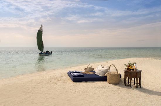 Picknick am goldenen Strand mit Segelboot im Hintergrund