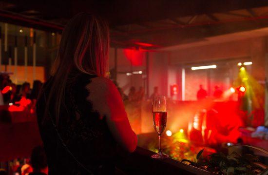 Silvester 2019/20 in Südafrika: Frau steht neben einem Glas Champagner und schaut bei einer Show zu