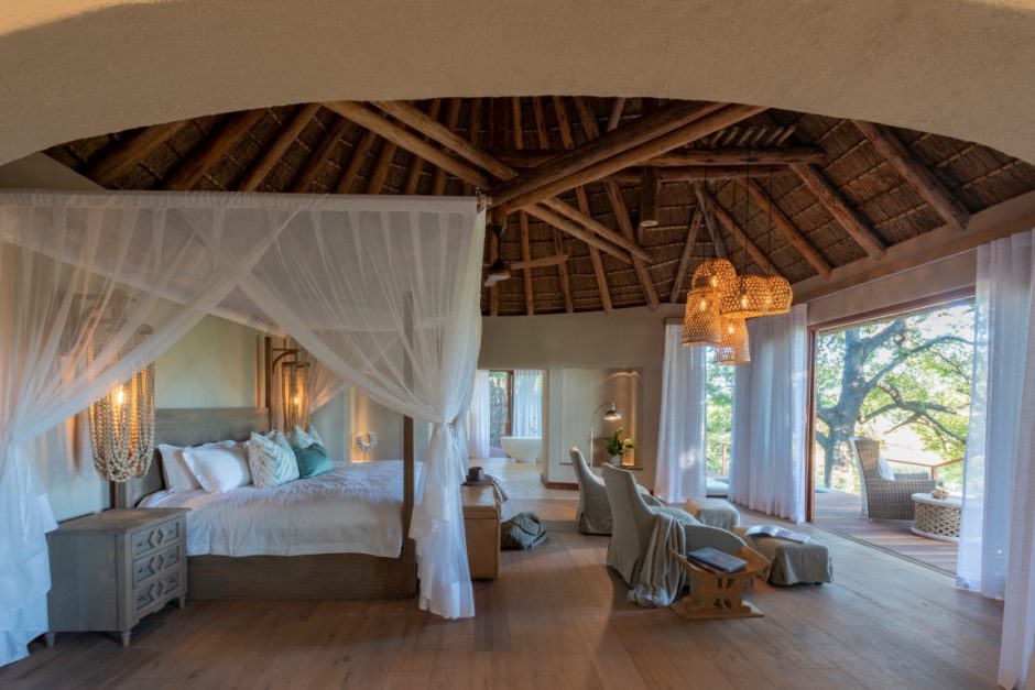 Eine Suite der Dulini River Lodge mit Bett, das auf ein Flussbett blickt