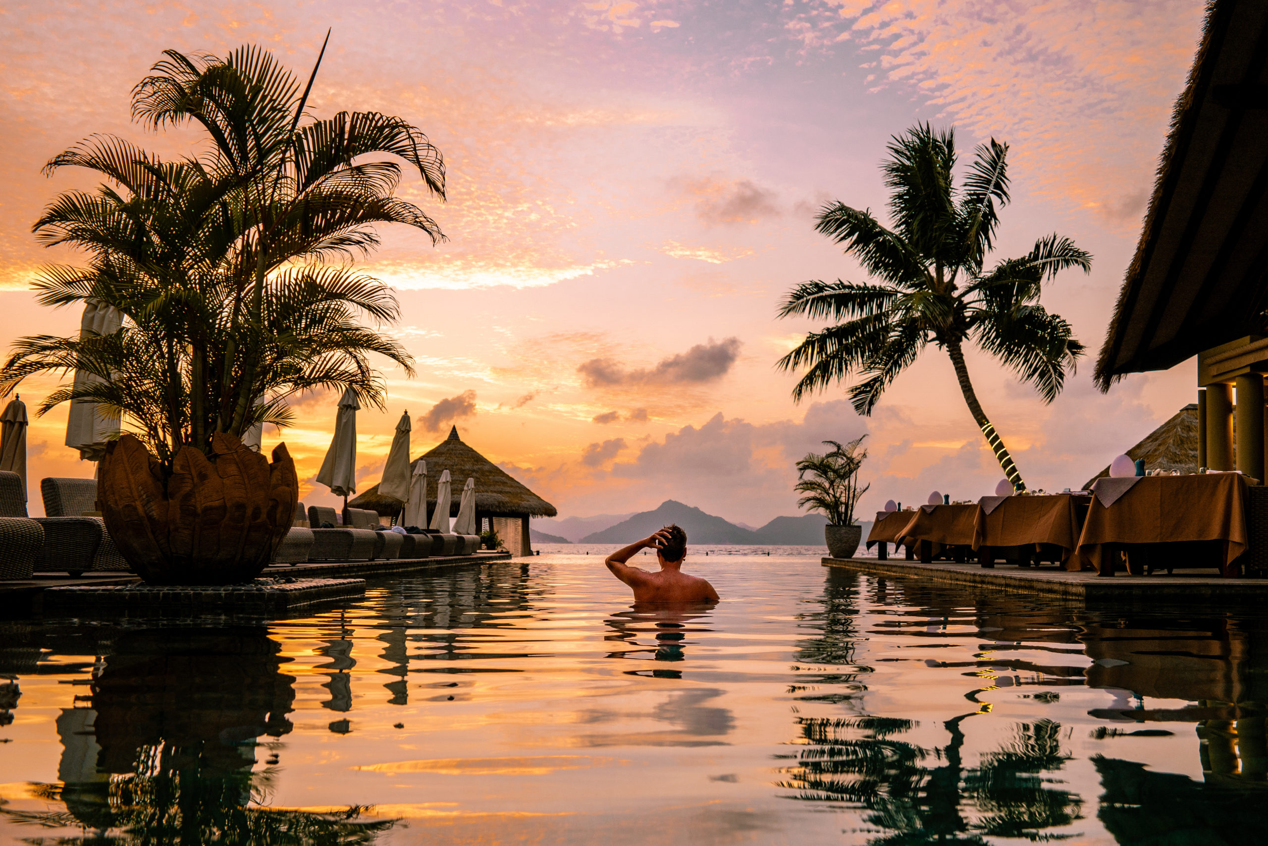 Sunset in Seychelles with man swimming in pool at resort