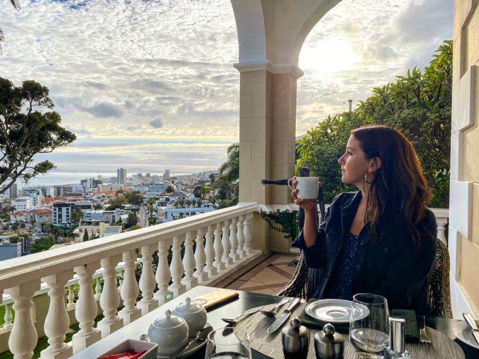 Woman sipping on a cup of coffe with the Cape Town behind her