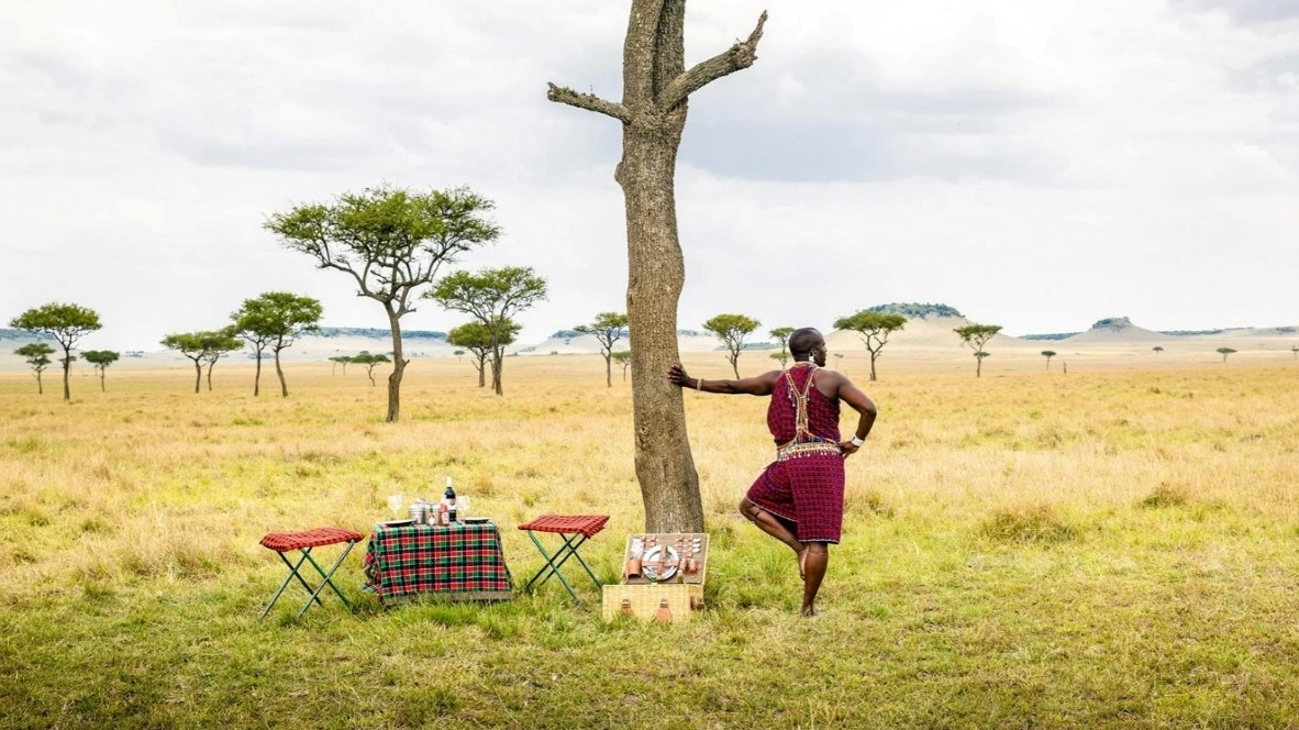 Maasai Mara tribal member gazing into the vast Mara plains while waiting for guests to arrive for their bush breakfast