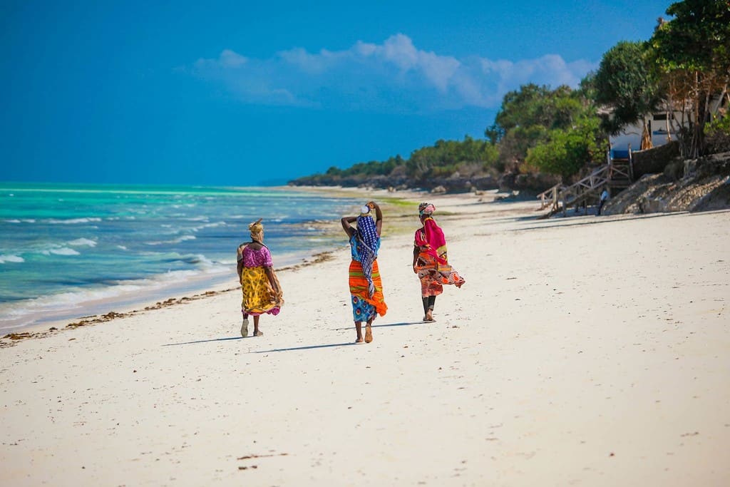 Three local women walking on the beach in Zanzibar