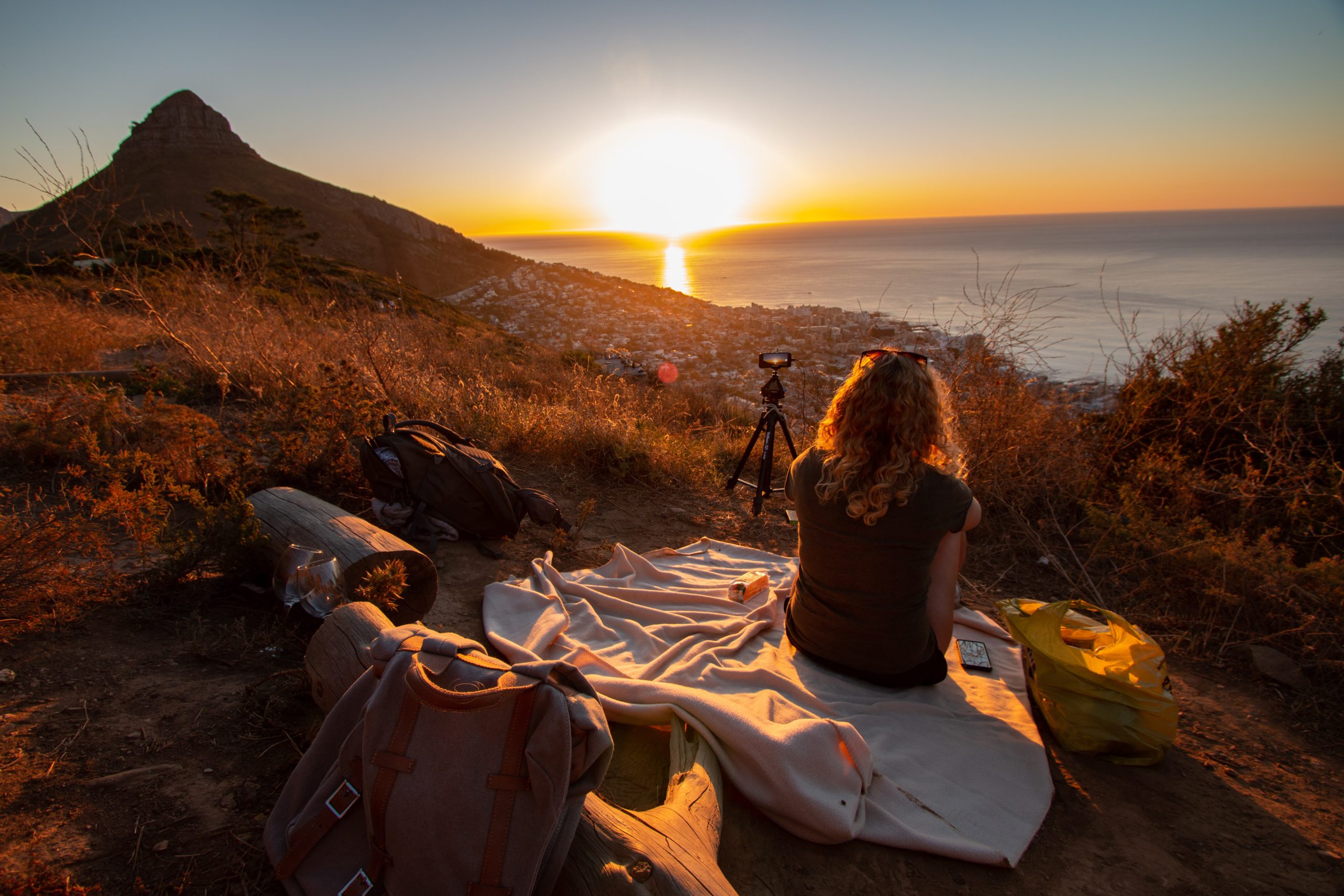 Woman sitting on a picnic blanket on Signal Hill in Cape Town watching the sunset