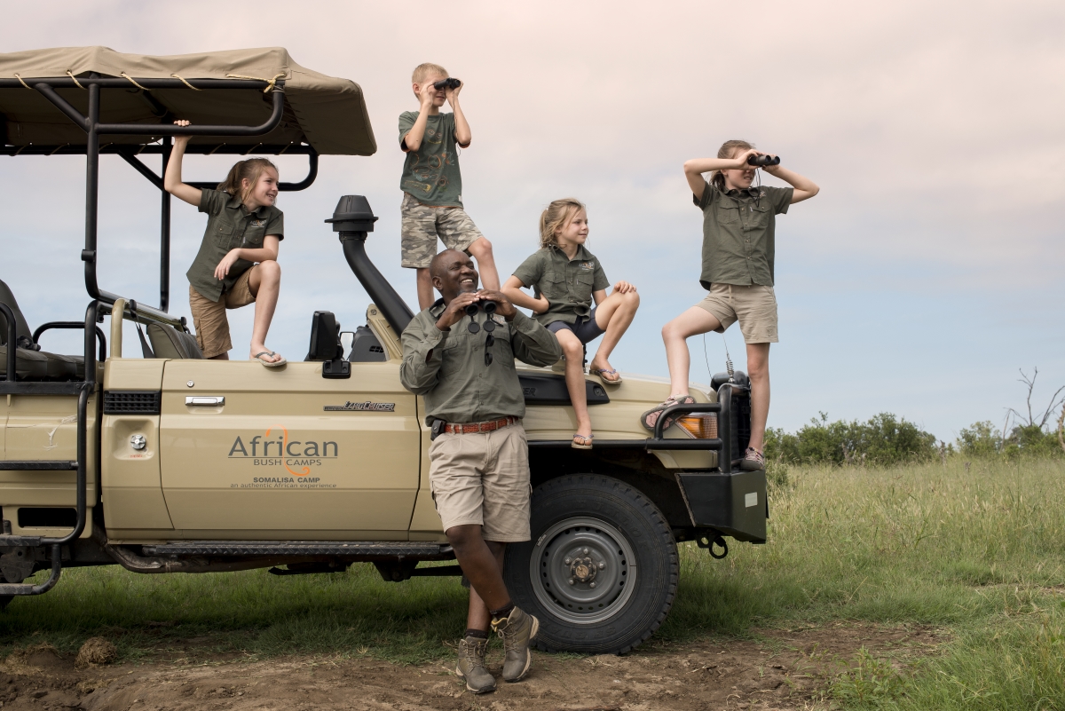 Four children on game drive vehicle with expert guide