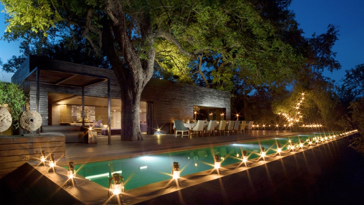 Lap pool and pool deck surrounded by lanterns in the evening