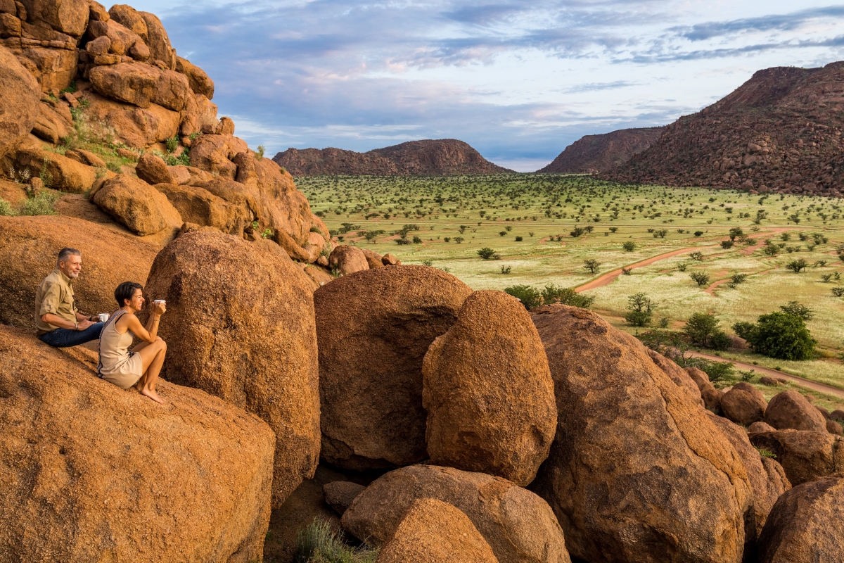 Couple resting on boulders during a walking safari in Damaraland