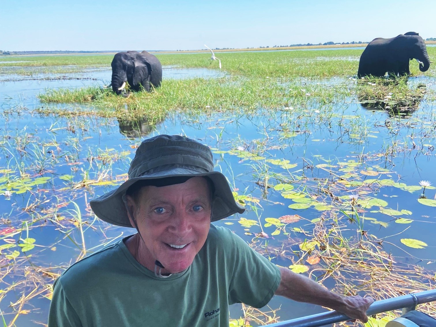 Tim on a river cruise with elephants nearby in the background