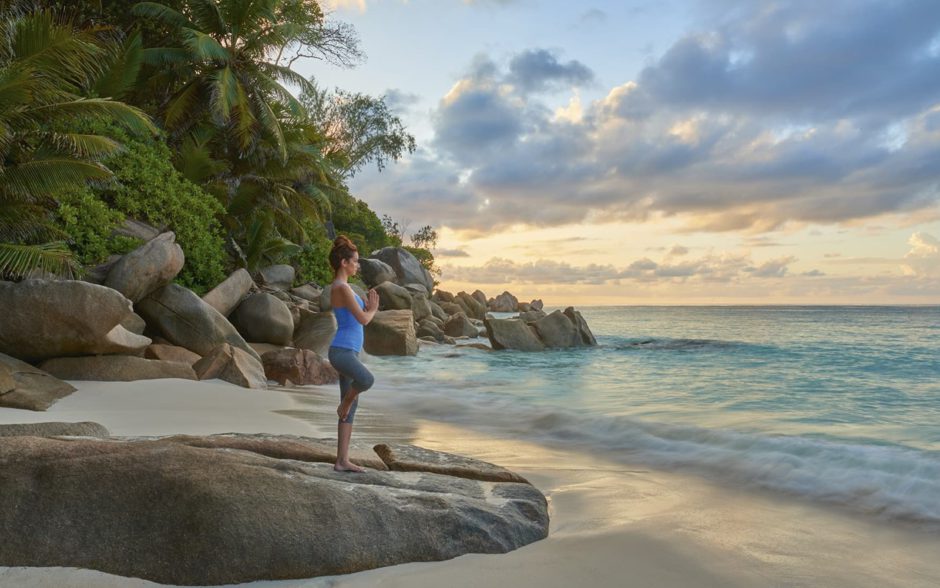 Woman doing yoga on a beach in Seychelles