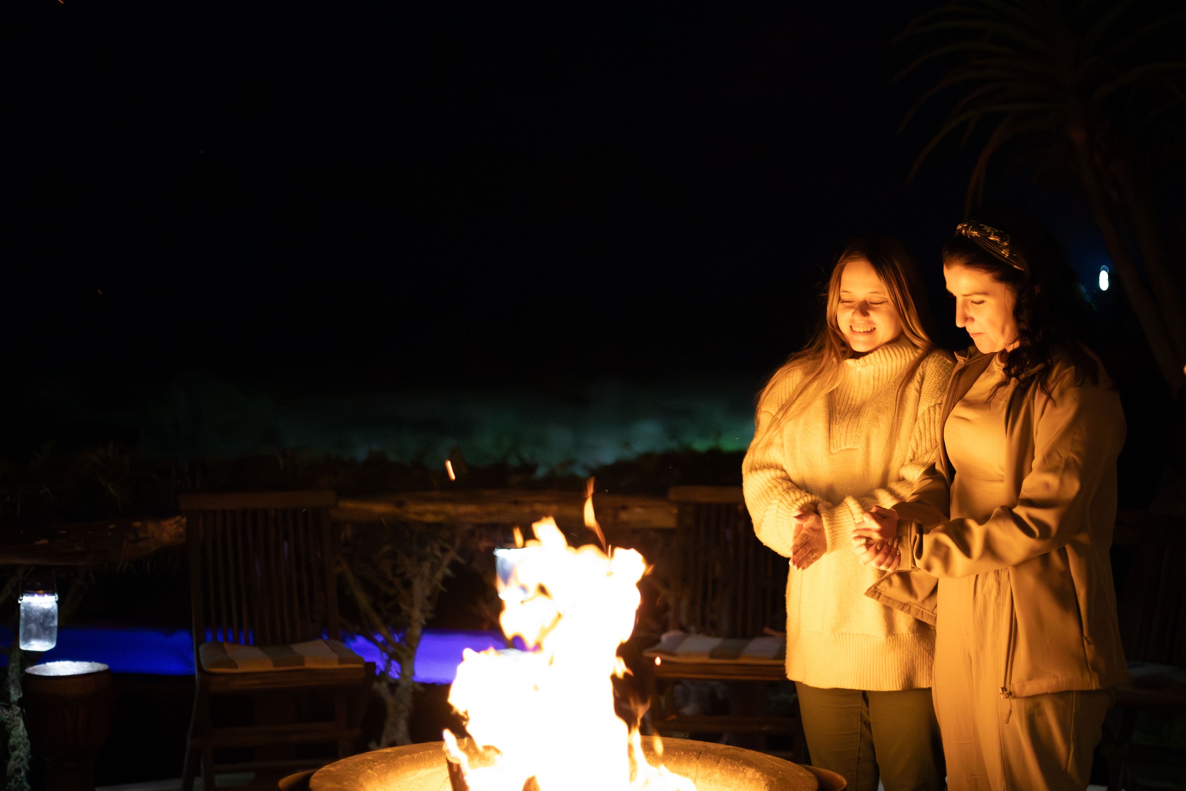 Two women standing around a fire at Amakhala Bush Lodge in Eastern Cape, South Africa