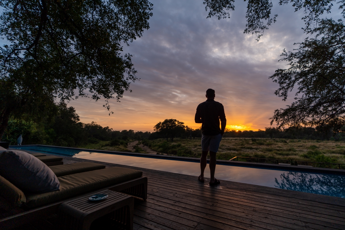 Pool deck at Silvan Safari with a view of the wilderness and dramatic stormy sky