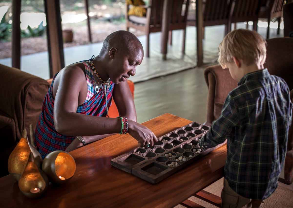 One of the guides playing a traditional African game with one of the child guests