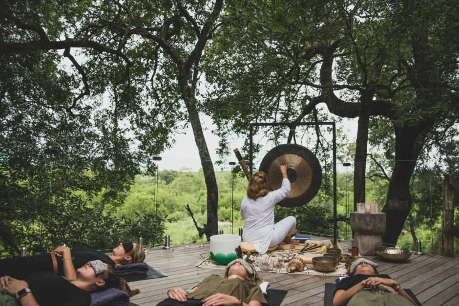 Woman meditating on wooden deck surrounded by nature