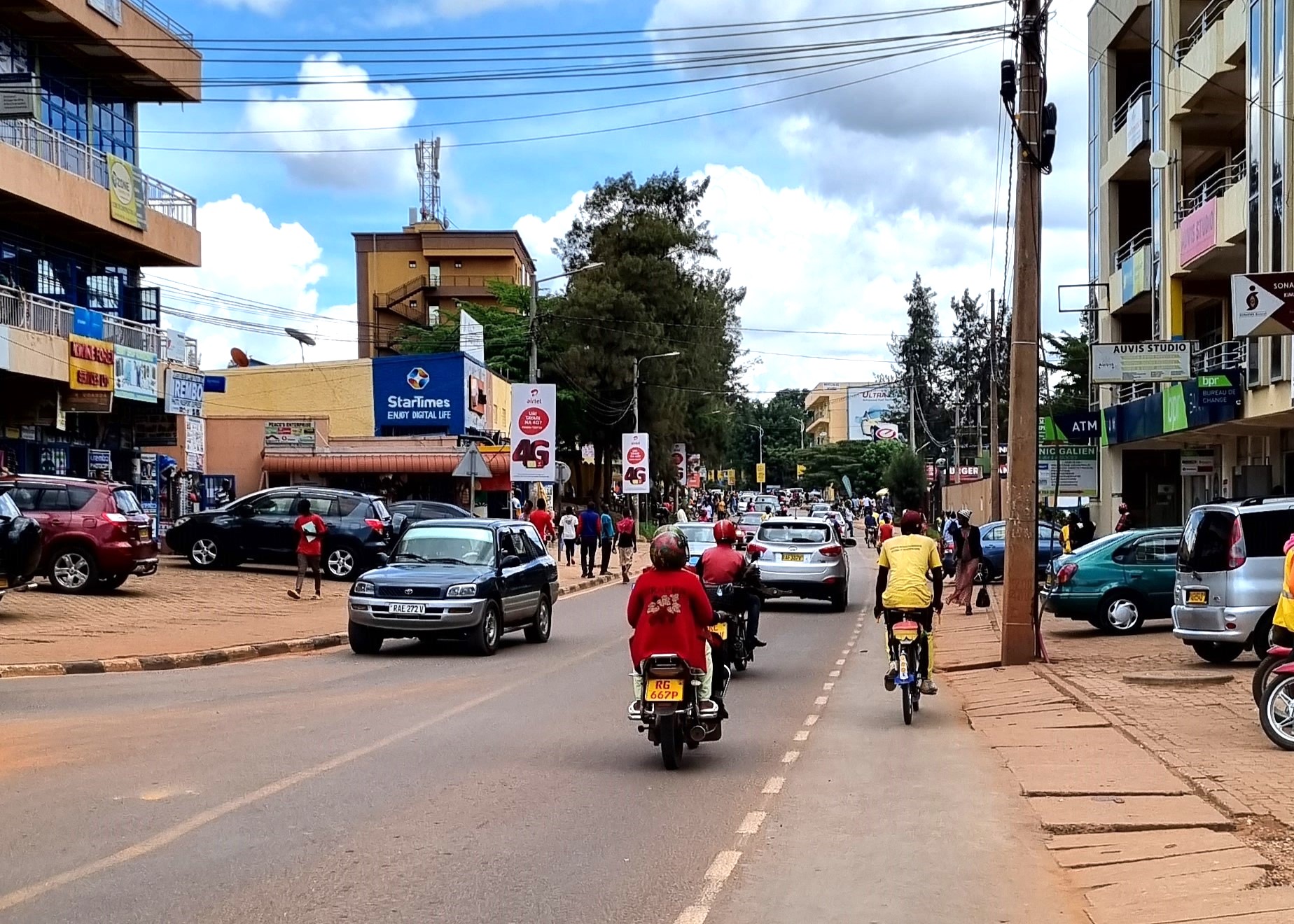 City street with vehicles, scooters and a cyclist, no litter in sight