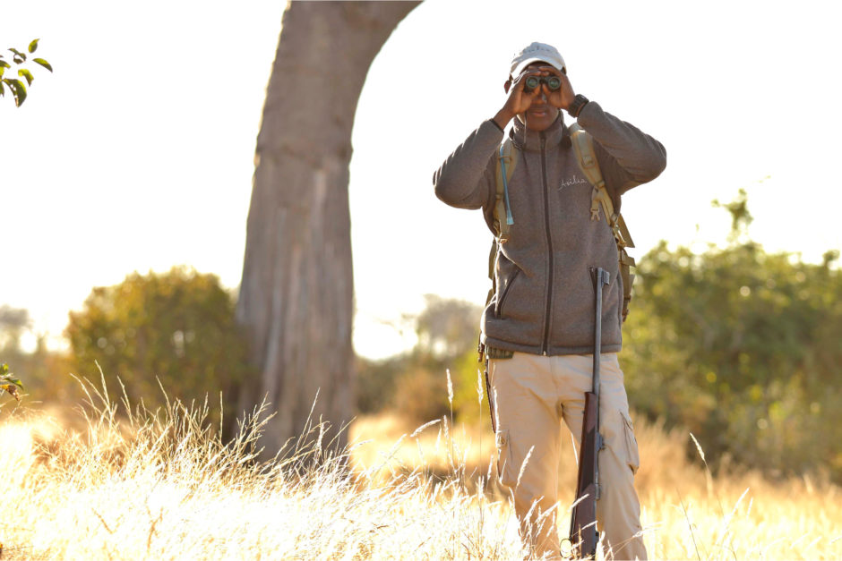 One of Asilia Africa's guides looking through a pair of binoculars